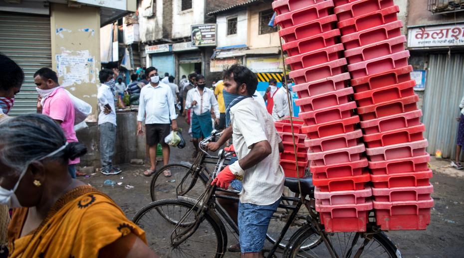 Milk vendor pushes bicycle through crowded market area in Dharavi slum during nationwide lockdown as a preventive measure against the spread of the COVID-19 coronavirus