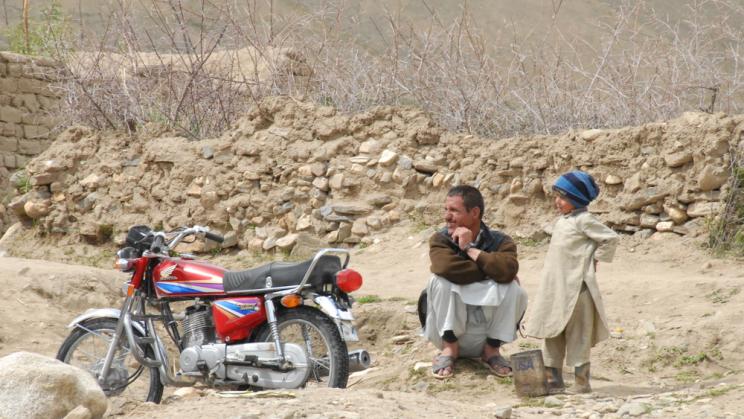 Man and boy sit next to a motorbike in Nechem, Afghanistan